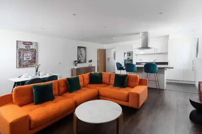 a living room with an orange couch and a kitchen at Barepta Cove, Stunning Carbis bay apartment in Carbis Bay