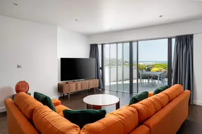 a living room with an orange couch and a flat screen tv at Barepta Cove, Stunning Carbis bay apartment in Carbis Bay