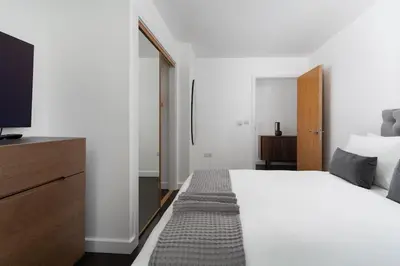 a bedroom with a large white bed and a tv at Barepta Cove, Stunning Carbis bay apartment in Carbis Bay