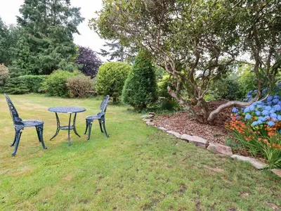 two chairs and a table in a garden at Pheasant View in Truro