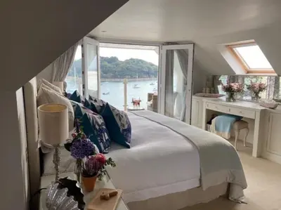 a bedroom with a bed with a view of the water at BBCFeatured LuxuryInteriorDesignedWaterfront Home. in Saint Mawes