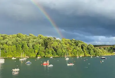 a rainbow over a body of water with boats at BBCFeatured LuxuryInteriorDesignedWaterfront Home. in Saint Mawes