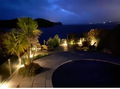 a view of a patio with a swimming pool at night at BBCFeatured LuxuryInteriorDesignedWaterfront Home. in Saint Mawes