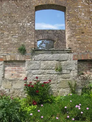 a brick wall with a window and flowers at The Coach House within heritage Tregrehan Garden on Cornwall's South Coast in Carlyon Bay