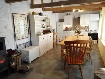 a kitchen with a table and a dining room at The Coach House within heritage Tregrehan Garden on Cornwall's South Coast in Carlyon Bay