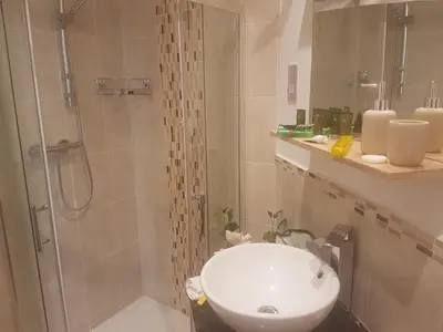 a bathroom with a white sink and a shower at Tregarth House in St Austell