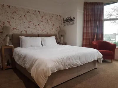 a bedroom with a large bed and a red chair at Tregarth House in St Austell