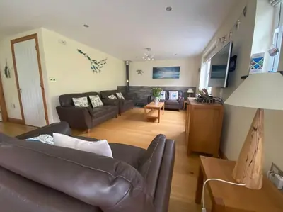 a living room with a leather couch and a table at Karrek View - Trebarwith Strand (Sleeps 8-10) in Treknow