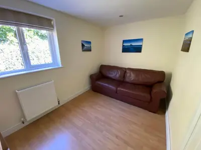 a living room with a brown leather couch and a window at Karrek View - Trebarwith Strand (Sleeps 8-10) in Treknow