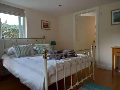 a bedroom with a bed and a window and a mirror at Karrek View - Trebarwith Strand (Sleeps 8-10) in Treknow