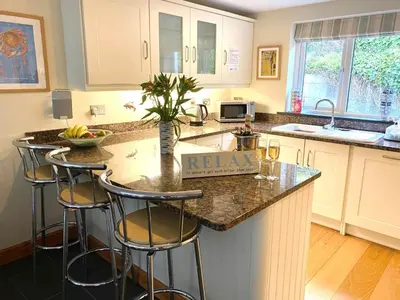 a kitchen with a island with bar stools at Karrek View - Trebarwith Strand (Sleeps 8-10) in Treknow