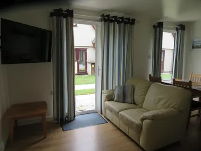 a living room with a couch and a sliding glass door at 11 Trevithick Court Tolroy Manor in Hayle
