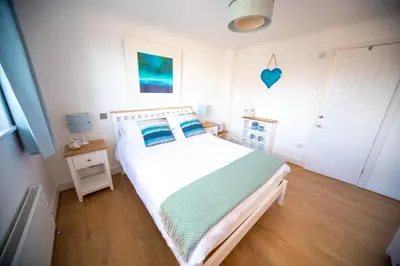 a bedroom with a white bed with blue pillows at Trethvor House FREE PARKING, Ensuite Double Quiet residential area in Padstow
