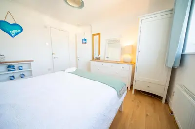 a bedroom with a white bed and a mirror at Trethvor House FREE PARKING, Ensuite Double Quiet residential area in Padstow