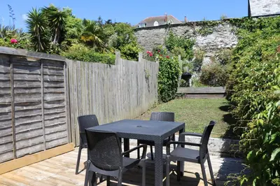 a table and chairs on a patio with a fence at Town centre apartment with parking in Padstow