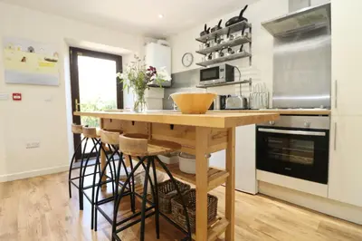 a kitchen with a wooden island with stools at Town centre apartment with parking in Padstow