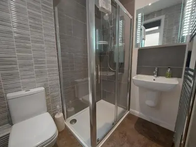 a bathroom with a shower and a toilet and a sink at Meadow View Apartments in Newquay