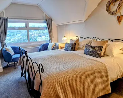 a bedroom with two beds and a window at Schooner Point Guest House in Looe