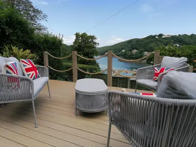 a deck with chairs and tables and a view of the water at Schooner Point Guest House in Looe