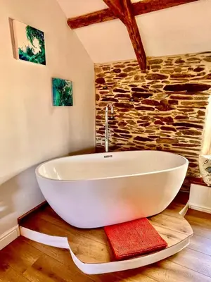 a white bath tub in a room with a stone wall at Just Opened. Romantic Clifftop Retreat in Portloe
