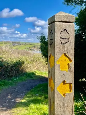 a wooden post with arrows on it on a road at Just Opened. Romantic Clifftop Retreat in Portloe