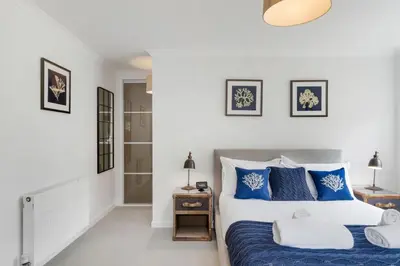 a bedroom with a bed with blue and white pillows at The Hawthorns in Polzeath