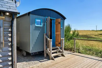 a blue shed with a door and a wooden ramp at Finest Retreats - Driftwood in Poundstock