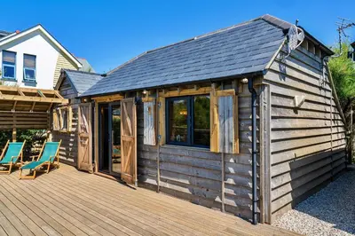 a cabin with a deck with two chairs on it at Finest Retreats - Driftwood in Poundstock