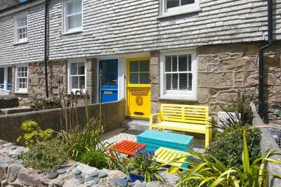 a yellow door and a yellow bench in front of a house at Puffin Cottage in St Ives