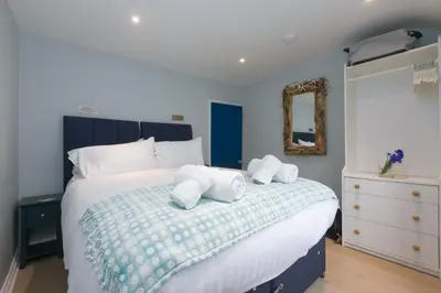 a bedroom with a blue and white bed with a mirror at Puffin Cottage in St Ives