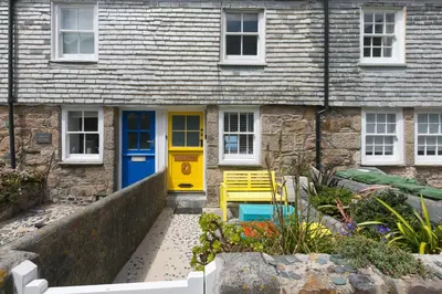 a yellow and blue door on a stone house at Puffin Cottage in St Ives