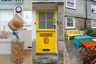 a yellow door on a house with a bench and a table at Puffin Cottage in St Ives