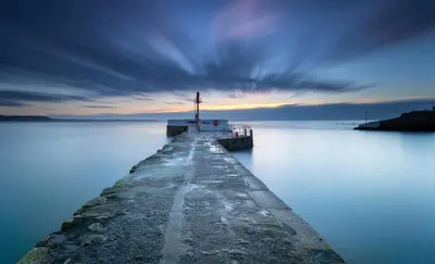 a pier on a body of water with a lighthouse at The Decker Apartment in Looe
