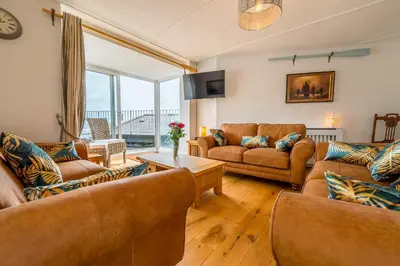 a living room with brown furniture and a large window at The Decker Apartment in Looe