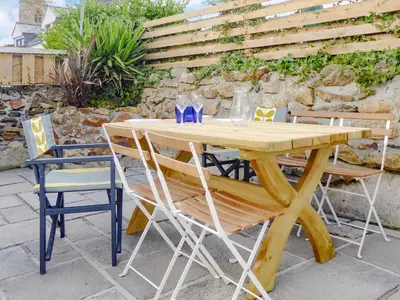 a wooden table and chairs with glasses on it at Churchtown Cottage in Cubert