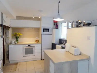 a kitchen with white cabinets and a white refrigerator at Churchtown Cottage in Cubert
