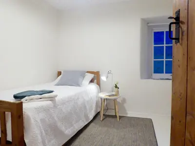 a bedroom with a bed and a table and a window at Churchtown Cottage in Cubert