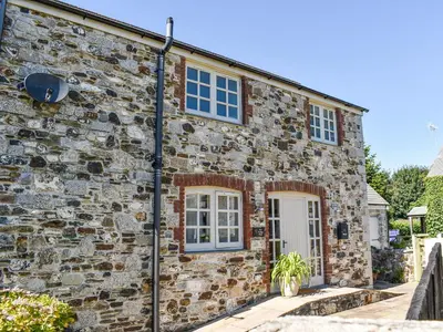 a stone house with a white door and windows at The Potting Shed in Par