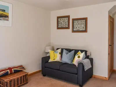 a living room with a black couch with colorful pillows at The Potting Shed in Par