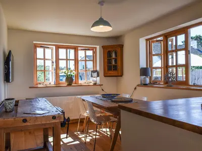 a kitchen with a table and chairs and windows at The Potting Shed in Par