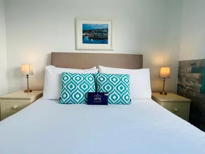 a bedroom with a large white bed with two lamps at Tremarne Hotel in Mevagissey