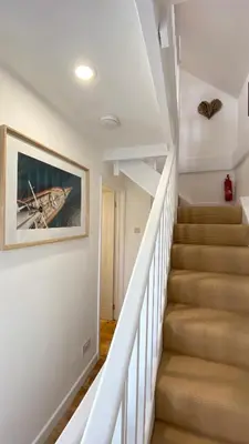 a staircase in a house with a painting on the wall at SMUGGLERS HIDE or SMUGGLERS CABIN - EITHER a 2 Bedroom FISHERMANS COTTAGE with Childs Bunk and HARBOUR VIEWS - OR a ground floor private small CABIN ROOM - 10 Metres To Sea Front - Book Both for a 3 Bed House - 2023 GLOBAL REFURBISHMENT AWARD WINNER in St Ives