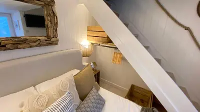 a stair room with a couch and a mirror at SMUGGLERS HIDE or SMUGGLERS CABIN - EITHER a 2 Bedroom FISHERMANS COTTAGE with Childs Bunk and HARBOUR VIEWS - OR a ground floor private small CABIN ROOM - 10 Metres To Sea Front - Book Both for a 3 Bed House - 2023 GLOBAL REFURBISHMENT AWARD WINNER in St Ives