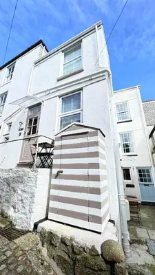a white building with a door in front of it at SMUGGLERS HIDE or SMUGGLERS CABIN - EITHER a 2 Bedroom FISHERMANS COTTAGE with Childs Bunk and HARBOUR VIEWS - OR a ground floor private small CABIN ROOM - 10 Metres To Sea Front - Book Both for a 3 Bed House - 2023 GLOBAL REFURBISHMENT AWARD WINNER in St Ives