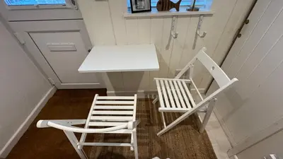 a table and two chairs next to a white table and chairs at SMUGGLERS HIDE or SMUGGLERS CABIN - EITHER a 2 Bedroom FISHERMANS COTTAGE with Childs Bunk and HARBOUR VIEWS - OR a ground floor private small CABIN ROOM - 10 Metres To Sea Front - Book Both for a 3 Bed House - 2023 GLOBAL REFURBISHMENT AWARD WINNER in St Ives