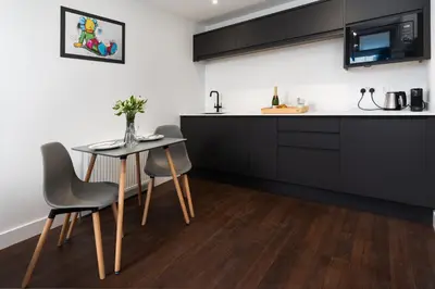a kitchen with black cabinets and a table and chairs at Room 2 Hotel style Double bedroom in Marazion in Marazion