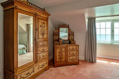a large wooden dresser in a bedroom with a mirror at Finest Retreats - Tregatreath in Coverack