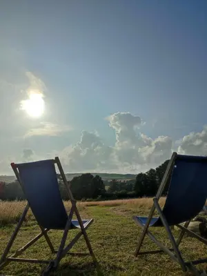 two chairs sitting in a field with the sun in the sky at Porthleven Glamping in Porthleven
