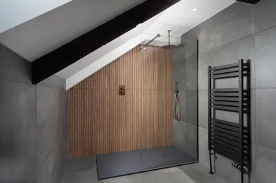 a bathroom with a shower with a wooden wall at Luxury Modern Suite in Marazion with Parking in Marazion