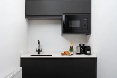 a kitchen with black cabinets and a plate of food at Room 1, Hotel style double bedroom in Marazion in Marazion